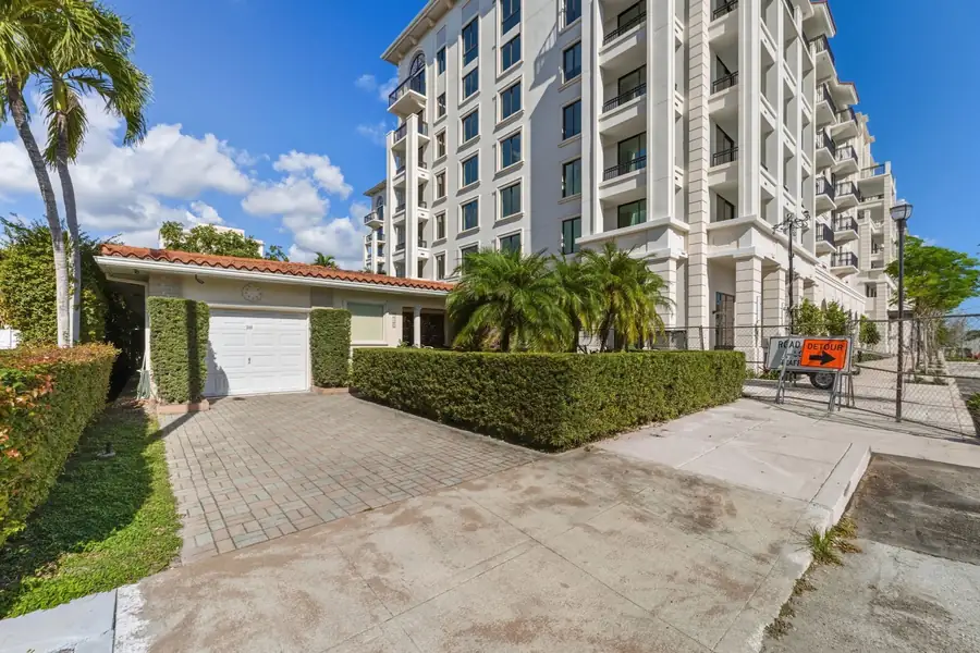 A tile-roofed house beside a mid-rise condominium building on a Coral Gables street