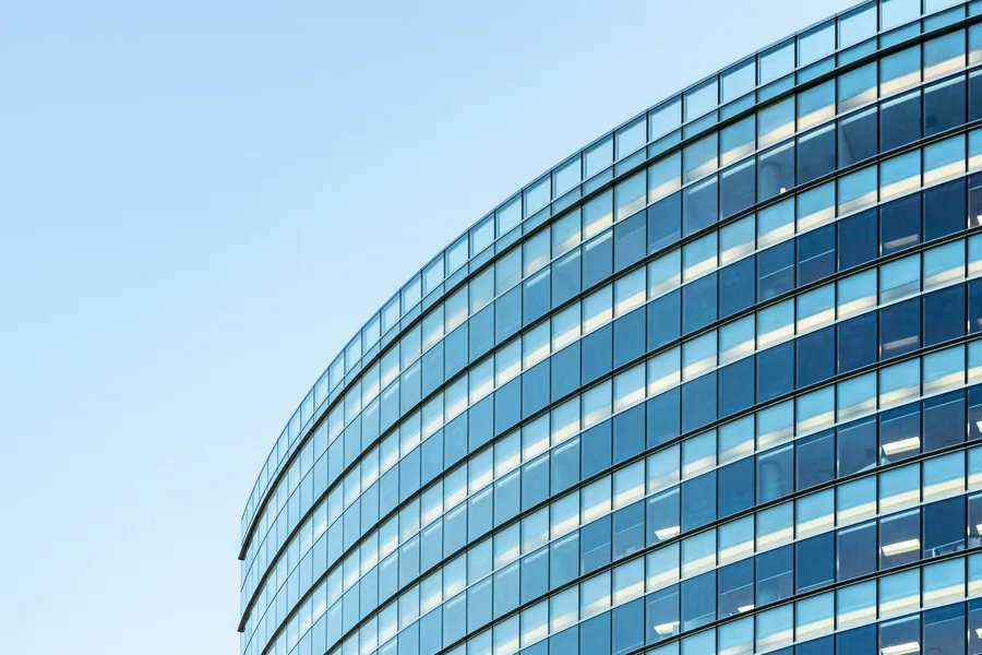 The curved glass facade of a Brickell condominium tower against a clear sky