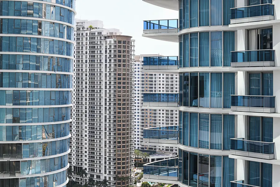 Residential towers packed close together in Brickell, curved blue glass beside a white balconied tower