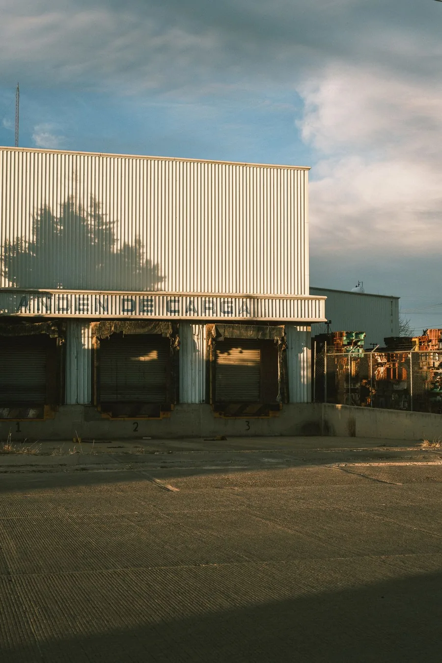 Three numbered dock-high loading positions in a metal-clad warehouse wall, under a sign reading ANDEN DE CARGA